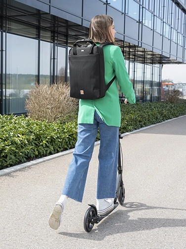 A young girl rides away from the viewer on an e-scooter with the Hama ‘Extreme Protect’ laptop rucksack on her back.